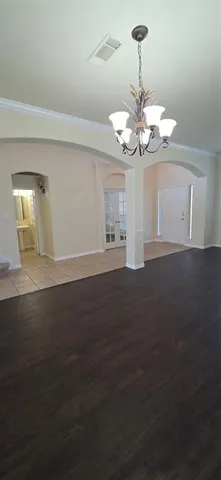 a view of an empty room with a chandelier fan
