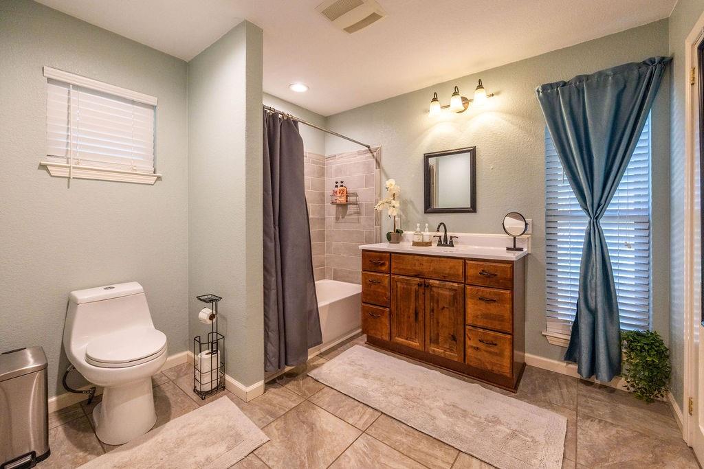 384 Ft Graham Road Waco, TX 76705 - Photo 13 of 36 Wood-finish vanity with white countertop, undermount sink, and matte black faucet