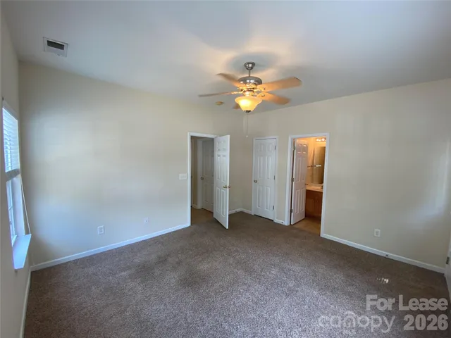 an empty room with chandelier fan and windows