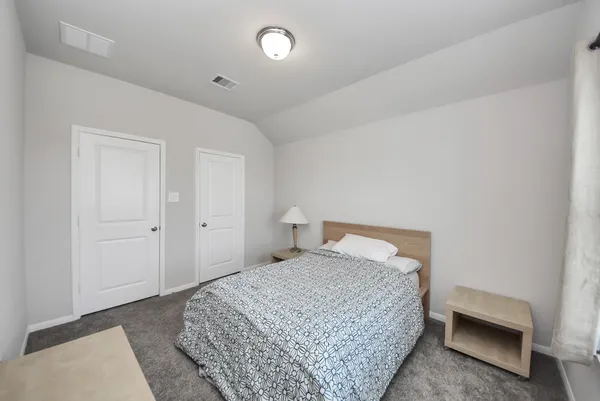 a bedroom with a bed and a lamp on the dresser