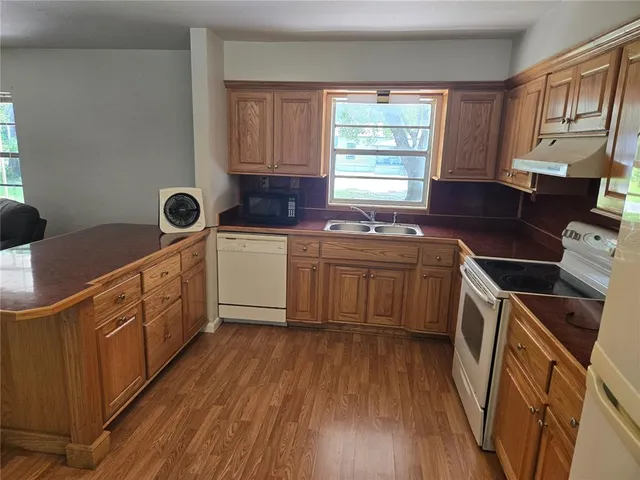 a kitchen with stainless steel appliances a sink dishwasher a stove top oven a refrigerator with wooden floor