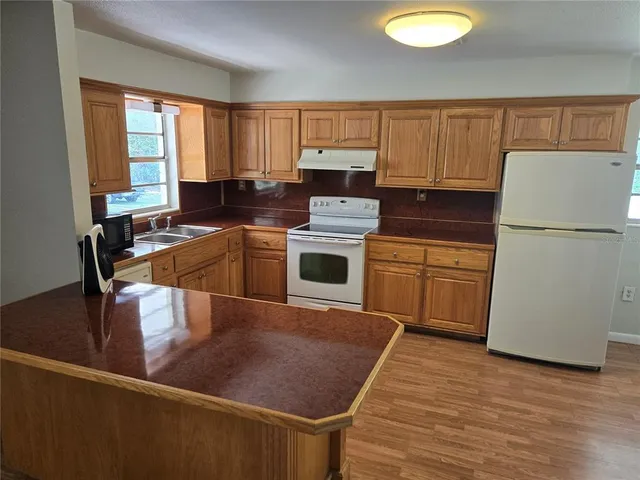 a kitchen with kitchen island a stove a sink dishwasher and a refrigerator with wooden floor