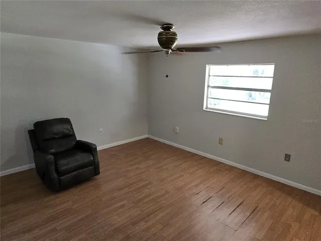 a view of room with wooden floor ceiling fan and windows