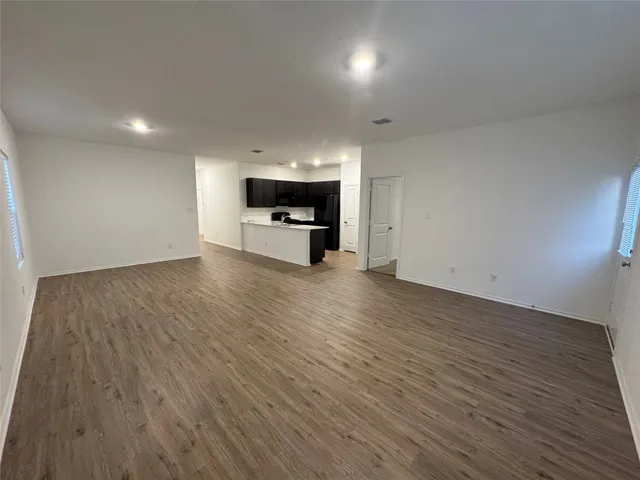an empty room with wooden floor a fireplace and windows