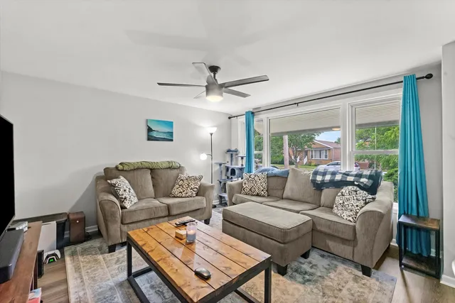 a living room with furniture a ceiling fan and a large window