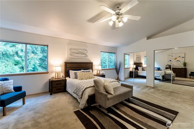 a bedroom with a large bed couch and windows