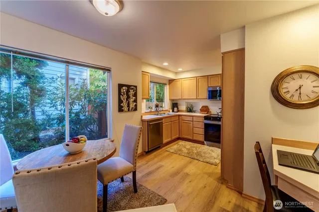 a kitchen with a refrigerator a stove top oven a sink dishwasher and a dining table with garden view