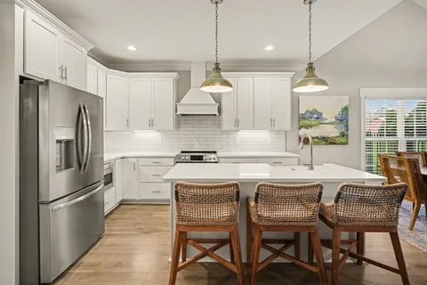 a kitchen with stainless steel appliances granite countertop a sink a stove a refrigerator a dining table and chairs