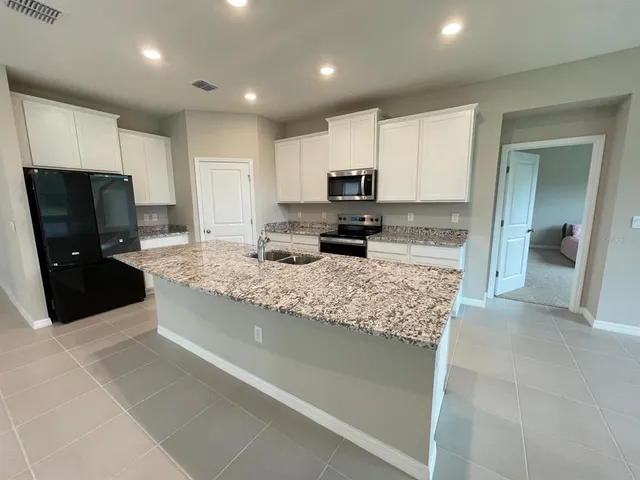 a large kitchen with kitchen island granite countertop a sink and a stove top oven