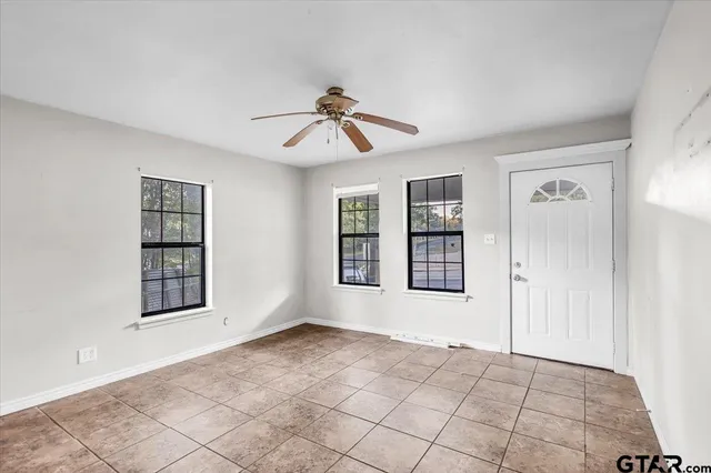 a view of an empty room with window and chandelier fan