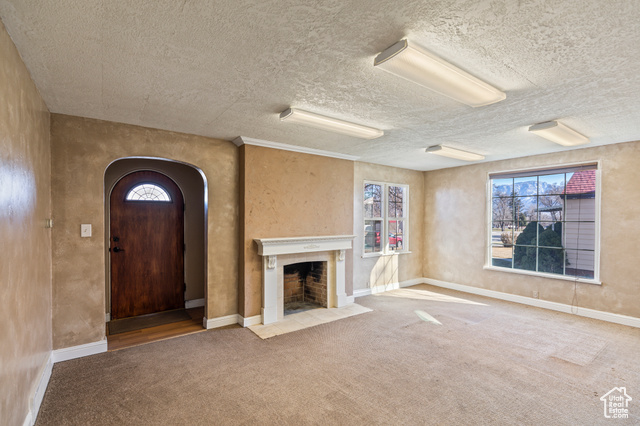465 North Main Street Richfield, UT 84701 - Photo 16 of 43 Unfurnished living room with carpet flooring, a fireplace with flush hearth, baseboards, and arched walkways