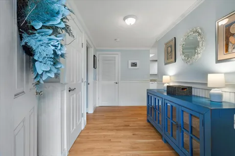 a view of a hallway to a bedroom with wooden floor and balcony