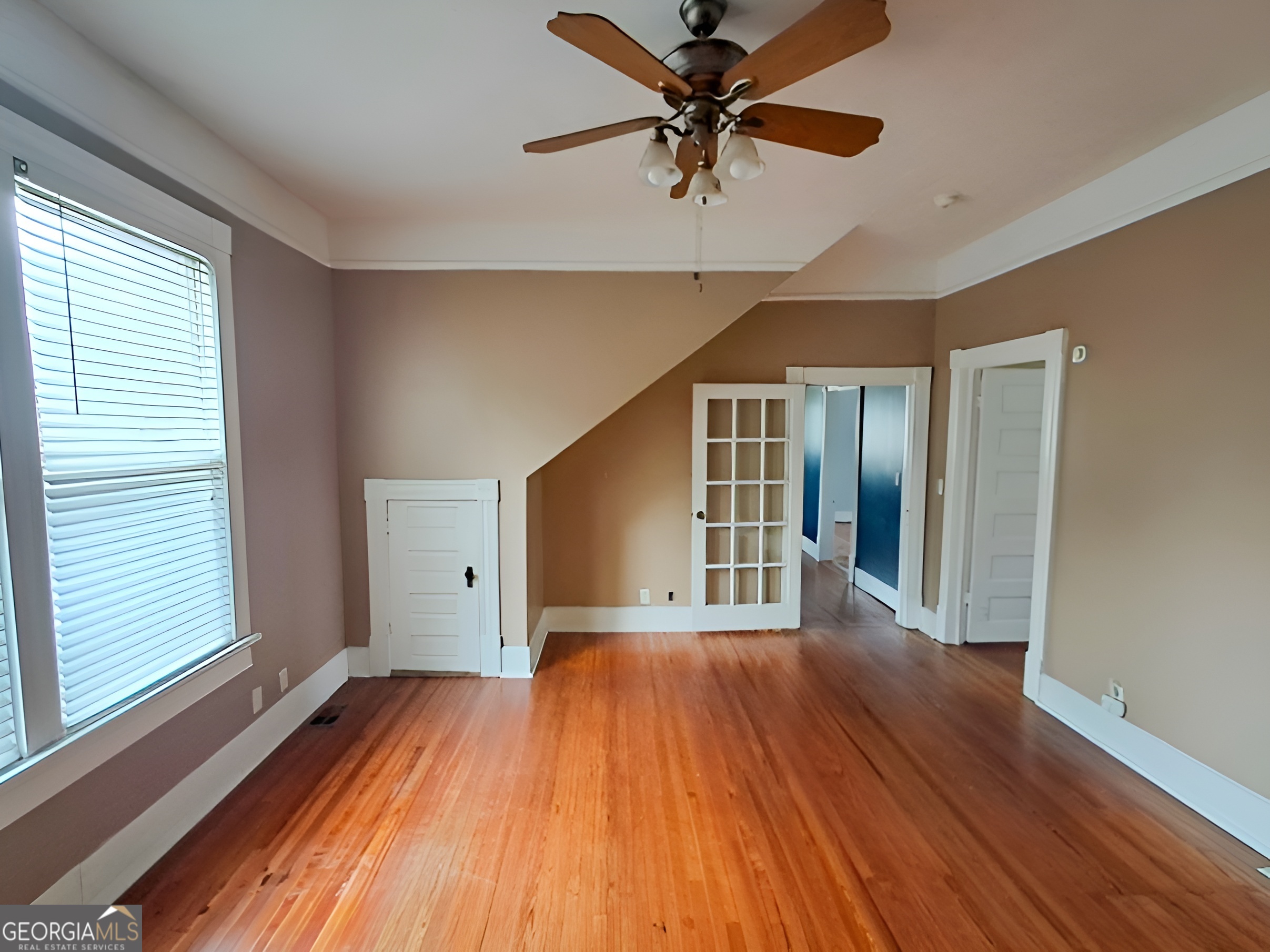401 Forsyth Street Barnesville, GA 30204 - Photo 7 of 25 a view of a big room with wooden floor a ceiling fan and windows