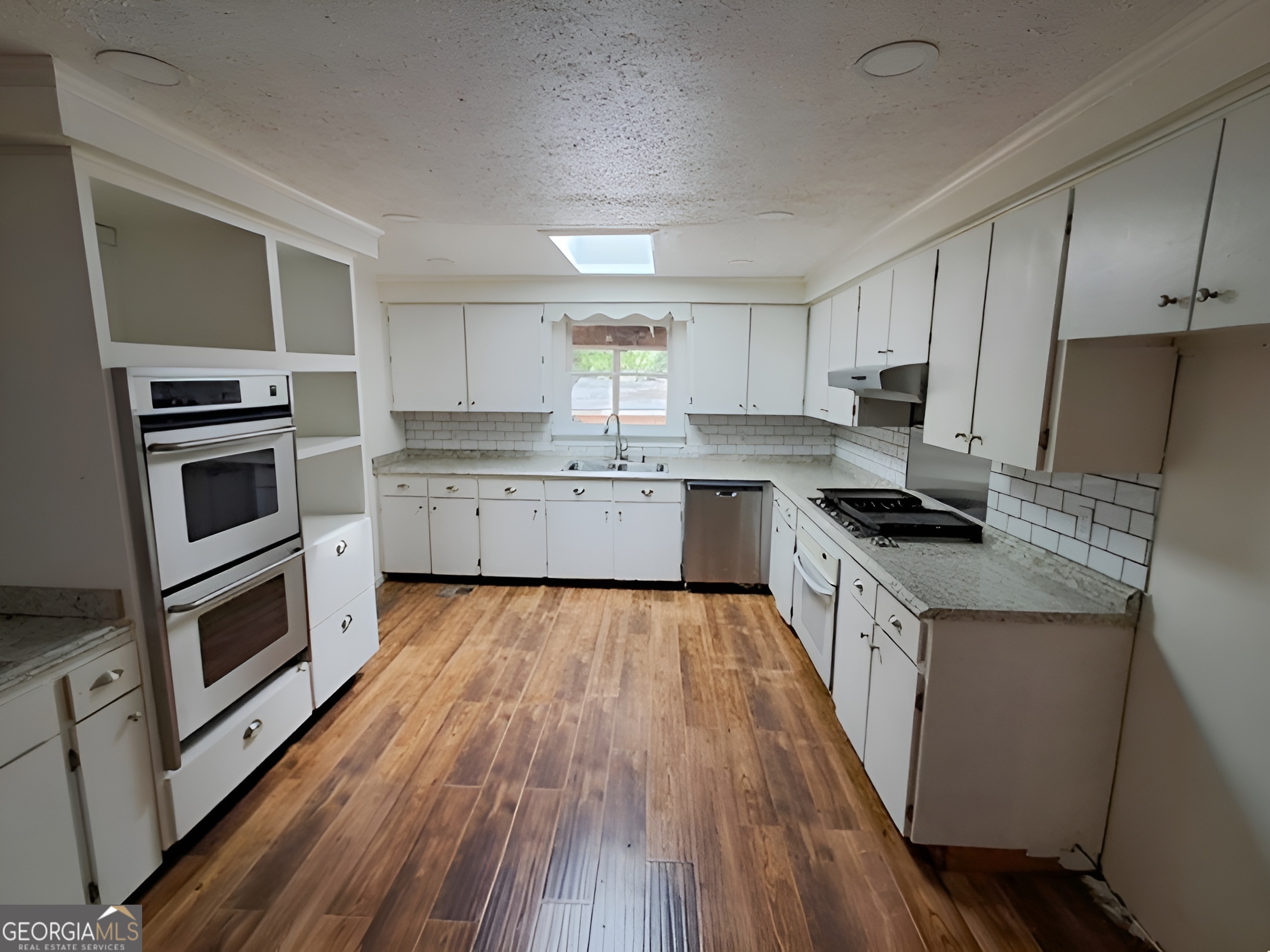 401 Forsyth Street Barnesville, GA 30204 - Photo 10 of 25 a large kitchen with cabinets wooden floor and stainless steel appliances