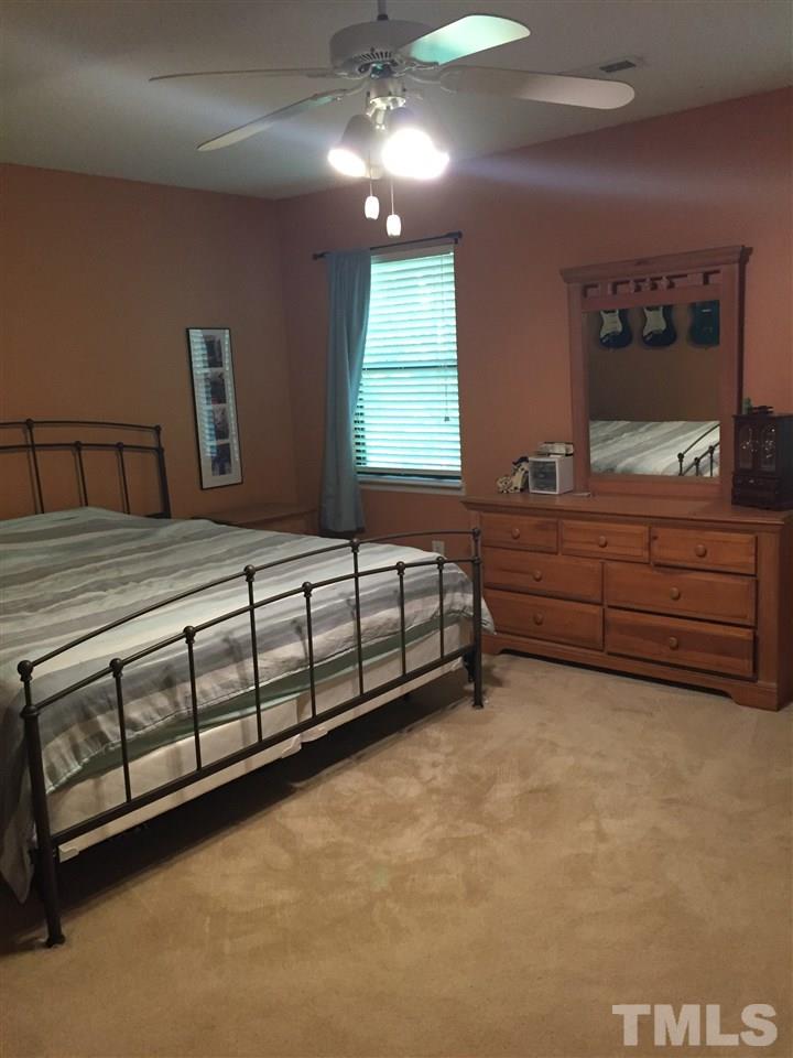 5702 3 Oaks Drive Raleigh, NC 27612 - Photo 9 of 18 a spacious bedroom with a bed a dresser and window