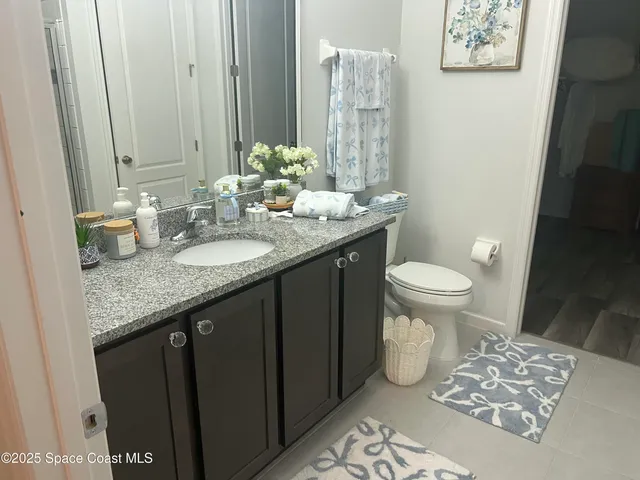 a bathroom with a granite countertop sink toilet and a mirror