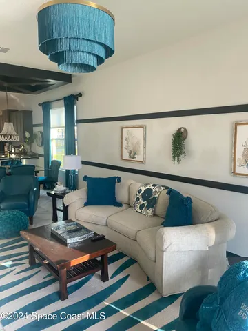 a living room with furniture a chandelier and a rug