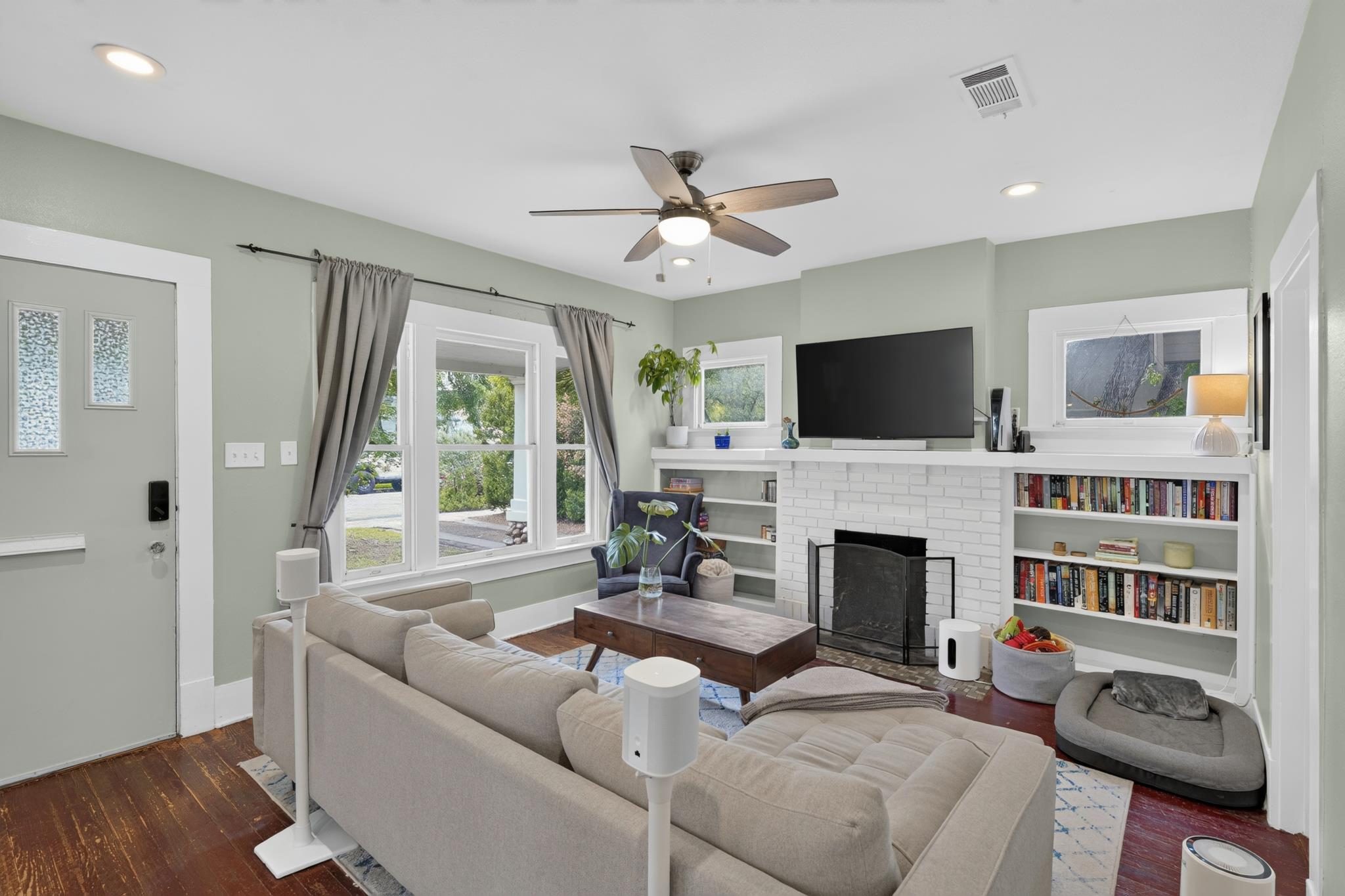 307 East 35th Street, Unit A Austin, TX 78705 - Photo 16 of 40 A comfortable living space boasts rich hardwood flooring and a classic brick fireplace, creating a cozy ambiance.