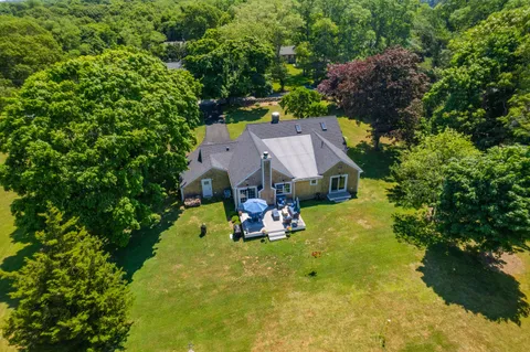 an aerial view of a house with swimming pool big yard and large trees