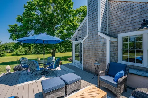 a view of a patio with couches table and chairs under an umbrella with a barbeque grill and couches