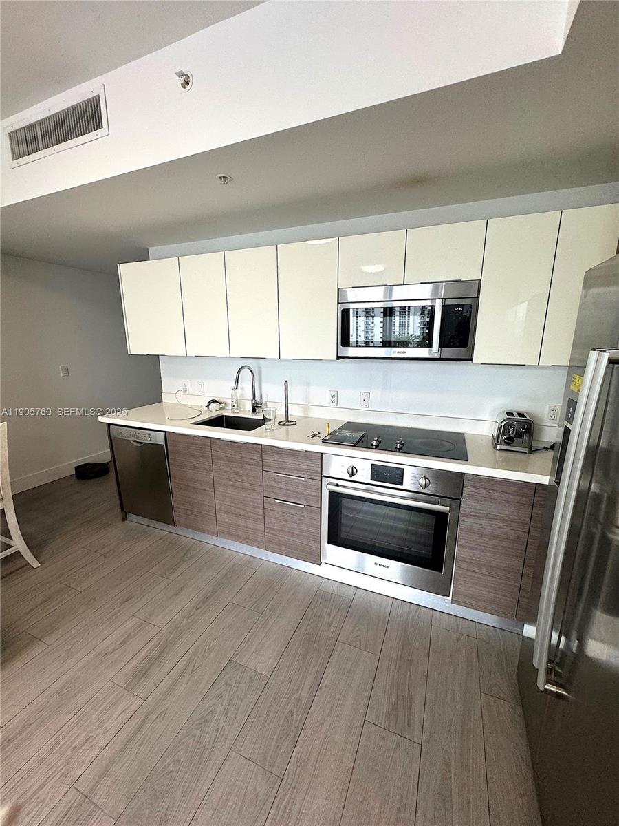 1010 Southwest 2nd Avenue, Unit 910 Miami, FL 33130 - Photo 4 of 32 a kitchen with stainless steel appliances a stove a sink and a refrigerator