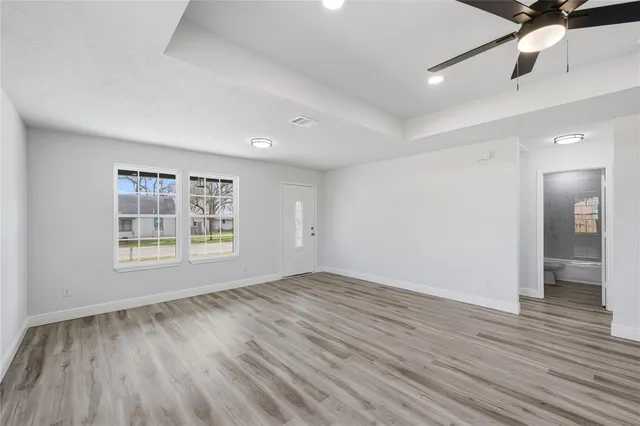 a view of an empty room with wooden floor and a window