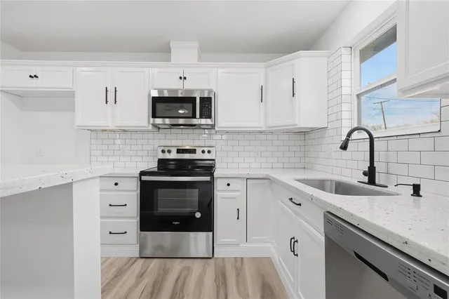 a kitchen with stainless steel appliances granite countertop a sink dishwasher a stove and a microwave oven with cabinets