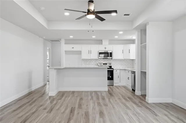 a kitchen with stainless steel appliances kitchen island hardwood floor sink and stove