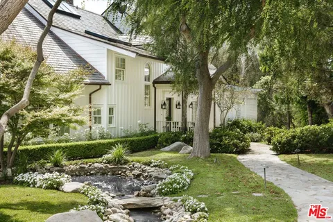 a view of a white house next to a yard with a fountain