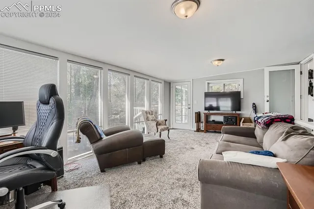 a living room with furniture a flat screen tv and a large window