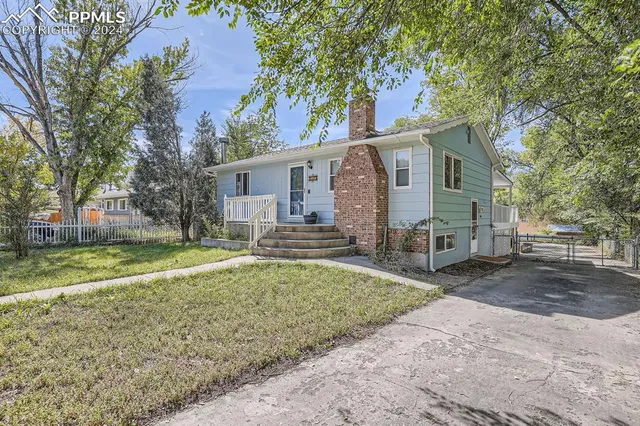 a view of a house with a yard and large tree