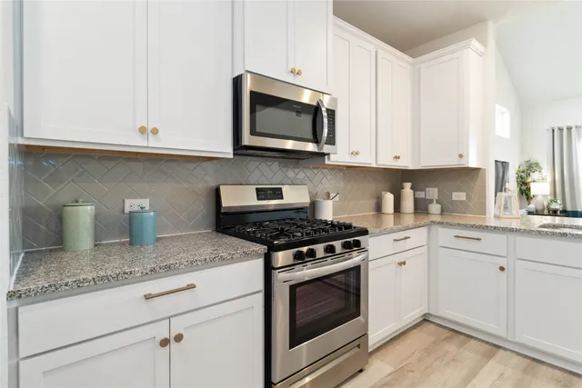 a kitchen with a sink dishwasher and a stove with wooden floor