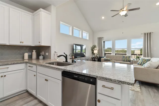 a kitchen with granite countertop white cabinets and stainless steel appliances