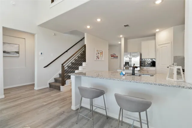 a kitchen with granite countertop a sink stainless steel appliances and white cabinets