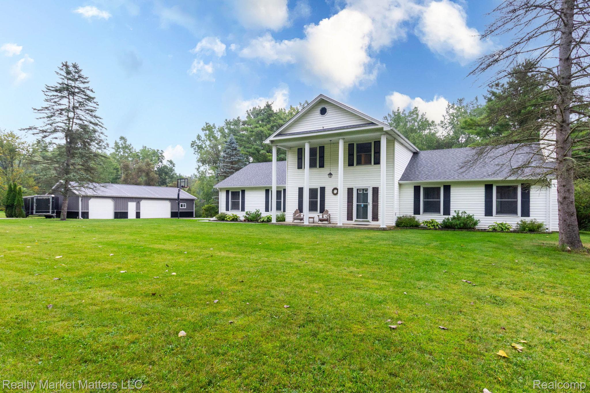 770 North Fairgrounds Road Imlay City, MI 48444 - Photo 2 of 55 Two-story Colonial-style residence featuring a prominent portico with four columns, white siding, and dark shutters