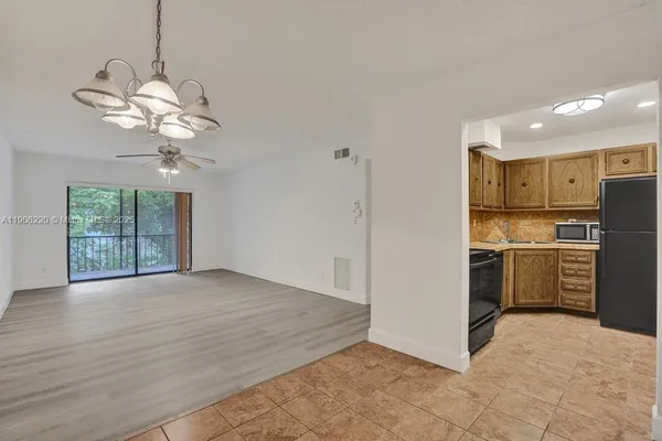 a view of a kitchen with a stove cabinets a ceiling fan and wooden floor
