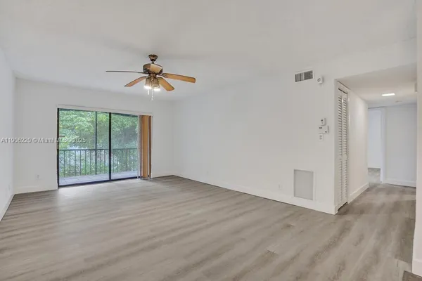 a view of a room with wooden floor and a ceiling fan
