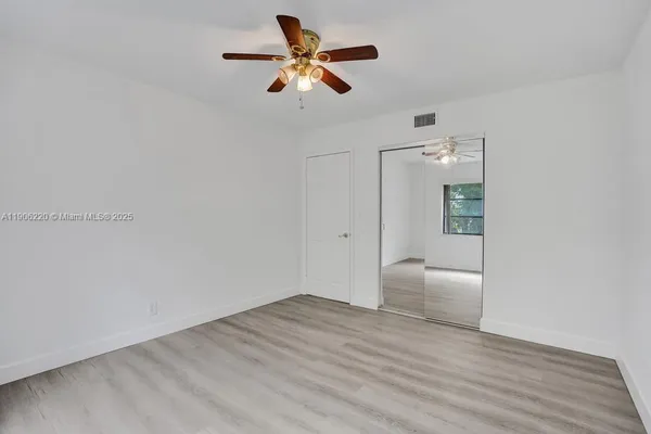 an empty room with wooden floor and ceiling fan