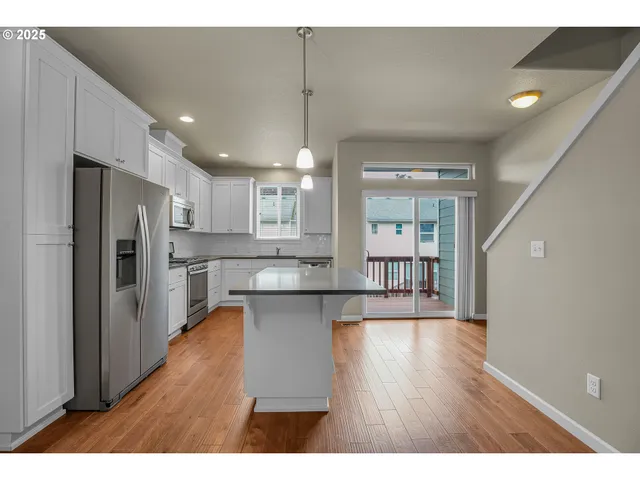 a open kitchen with kitchen island wooden floors appliances and center island