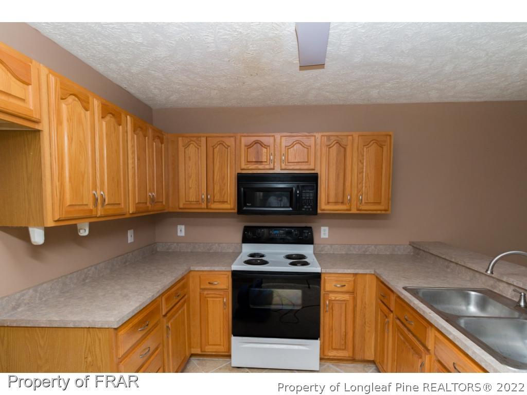 1941-3 Sardonyx Road Fayetteville, NC 28303 - Photo 10 of 27 a kitchen with granite countertop a sink a stove top oven and cabinetry