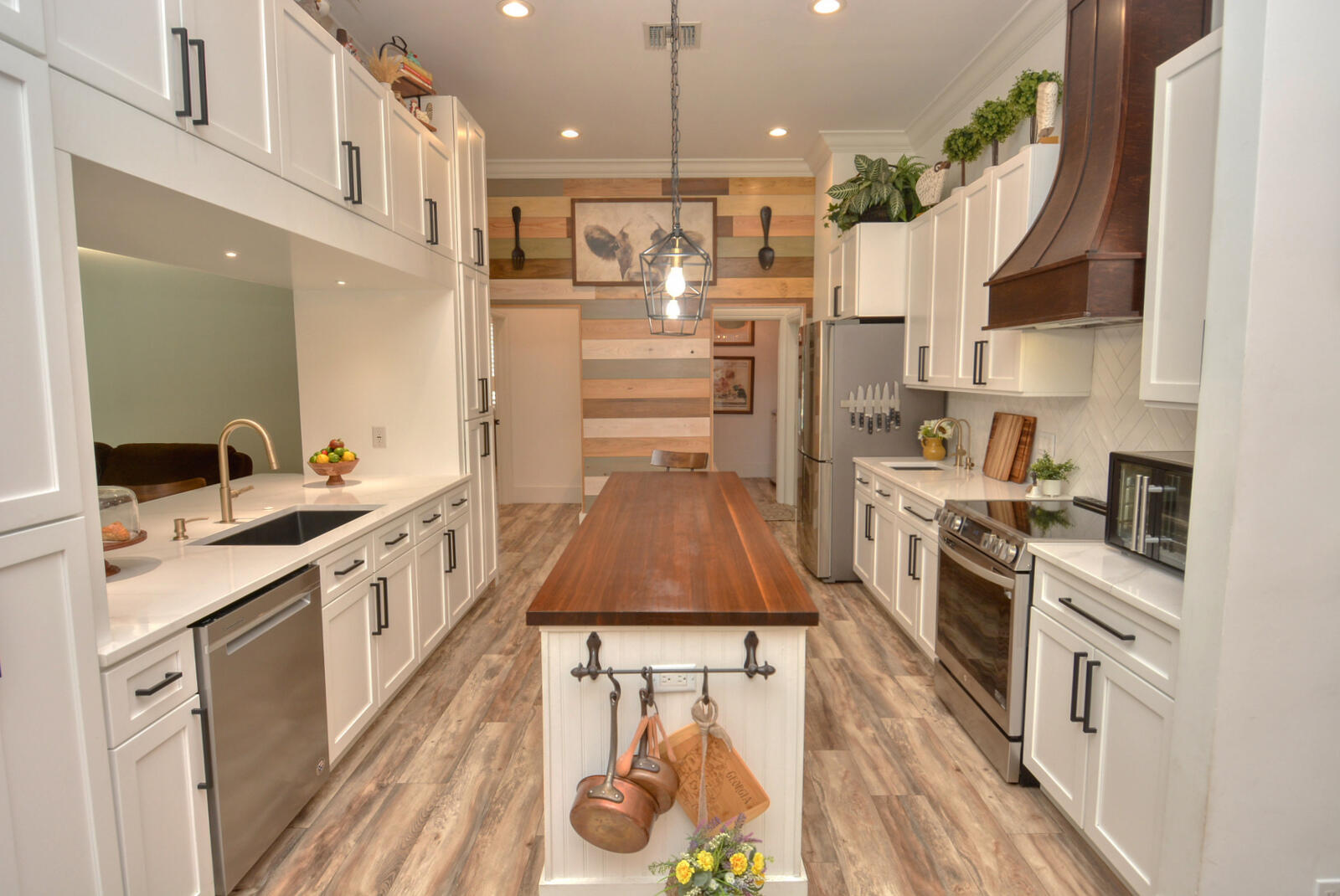 a kitchen with stainless steel appliances a stove a sink dishwasher a refrigerator white cabinets and wooden floor