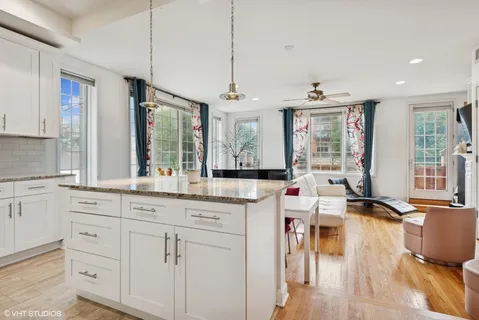 a open kitchen with granite countertop a stove a sink a dining table and chairs with wooden floor