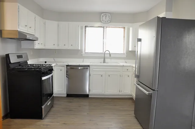 a kitchen with stainless steel appliances granite countertop a refrigerator sink and white cabinets