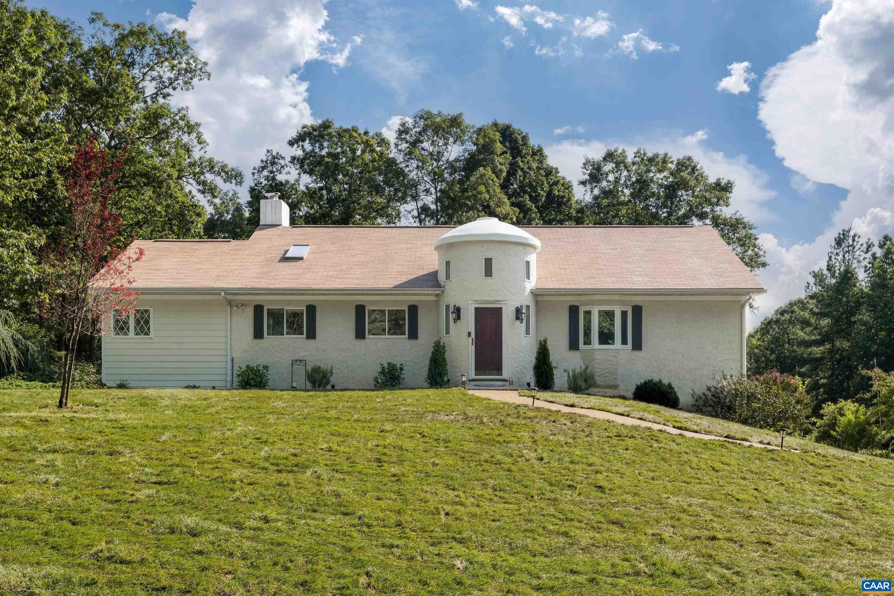 a front view of a house with yard and large trees