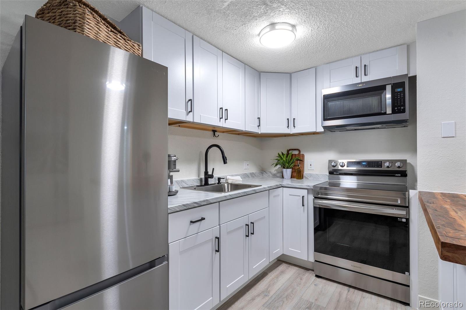 2500 South York Street, Unit 107 Denver, CO 80210 - Photo 6 of 21 a kitchen with granite countertop cabinets stainless steel appliances and a sink