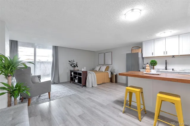 a living room with furniture and potted plants with wooden floor