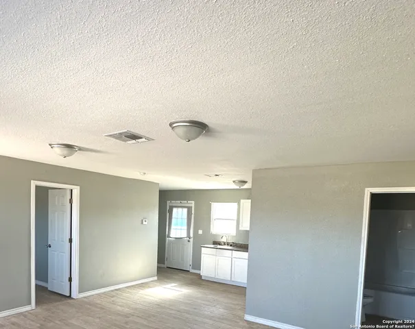 a view of a hallway with wooden floor and a cabinet