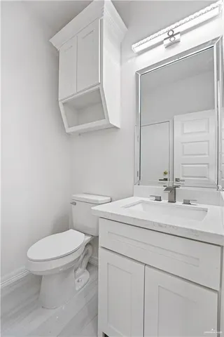 a bathroom with a toilet sink vanity and mirror
