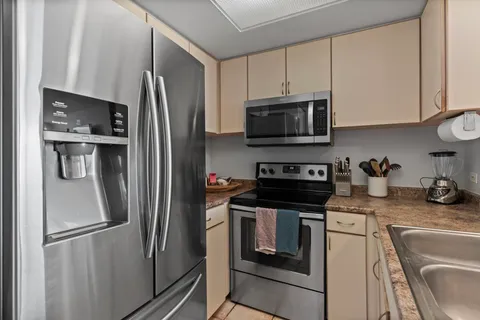 a kitchen with stainless steel appliances granite countertop a refrigerator a stove a sink and white cabinets