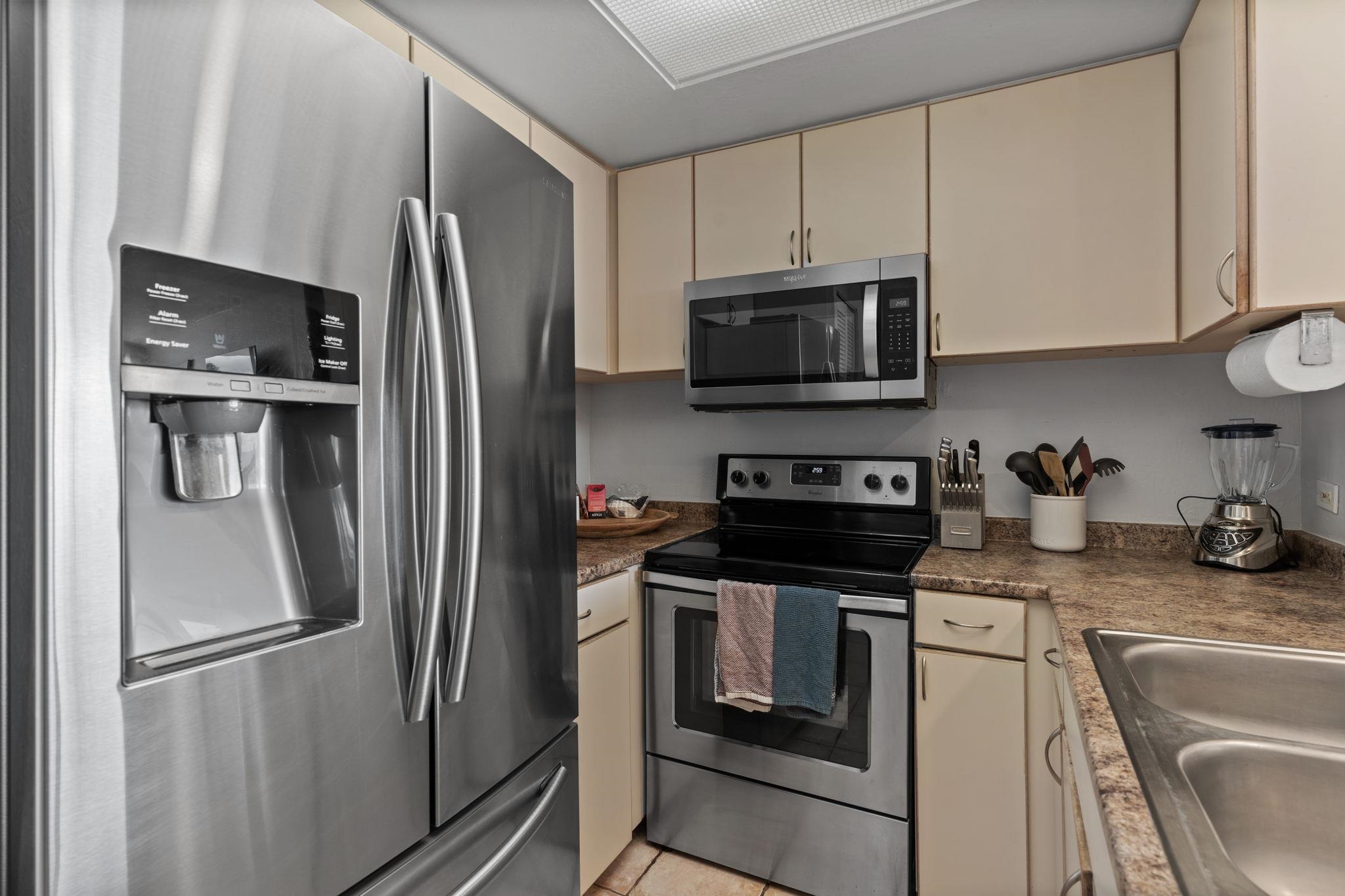 4401 Lower Honoapiilani Road, Unit A101 Lahaina, HI 96761 - Photo 5 of 37 a kitchen with stainless steel appliances granite countertop a refrigerator a stove a sink and white cabinets